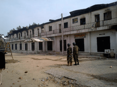 In this photo taken with a mobile phone, soldiers stand outside a burnt out shopping mall in Maiduguri, Nigeria, Monday, Oct. 8, 2012. Nigerian soldiers angry about the killing of an officer razed buildings and shot dead more than 30 civilians Monday in a northeastern city long under siege by a radical Islamist sect. An Associated Press reporter in Maiduguri, the spiritual home of the sect known as Boko Haram, counted the dead while on a tour of the still-smoldering neighborhood." (AP Photo / Abdulkareem Haruna) ( Abdulkareem Haruna )