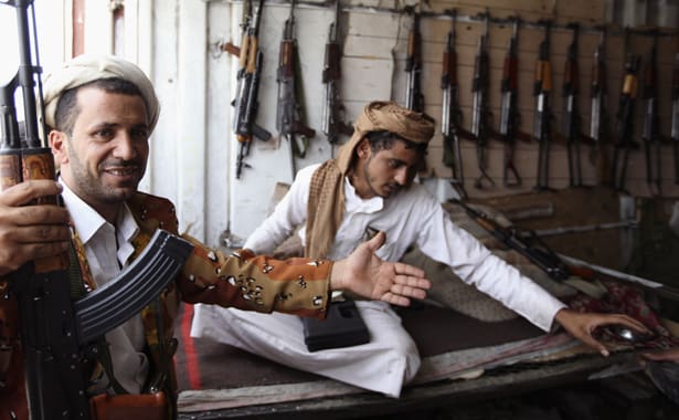 Man gestures whilst holding a gun at a weapons store in a market in Arhab