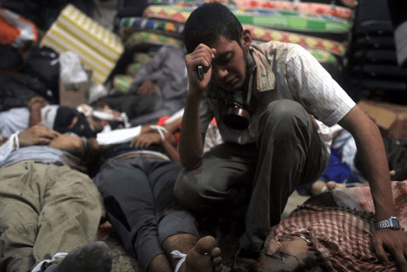 "A young man next to the bodies of protesters killed on Wednesday. Many of the dead were shot in the head or chest; some appeared to be in their early teens." (caption and photo courtesy nytimes.com)