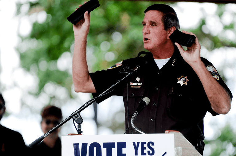  "Weld County Sheriff John Cooke holds up two identical rifle ammunition magazines, one obtained legally and one obtained illegally, while making a speech last week to supporters of the recall election to oust Senate President John Morse, who voted for a 15-round limit on magazines." (Caption and photo courtesy thepressherald.com) 
