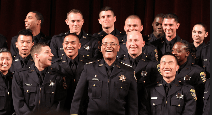 "Police Chief Howard Jordan jokes with the graduates of the 166th Basic Academy as they take a group photo at the end of the ceremony at the Scottish Rite Temple in Oakland, Calif., on Friday, March 22, 2013." (caption and photo courtesy mercurynews.com)