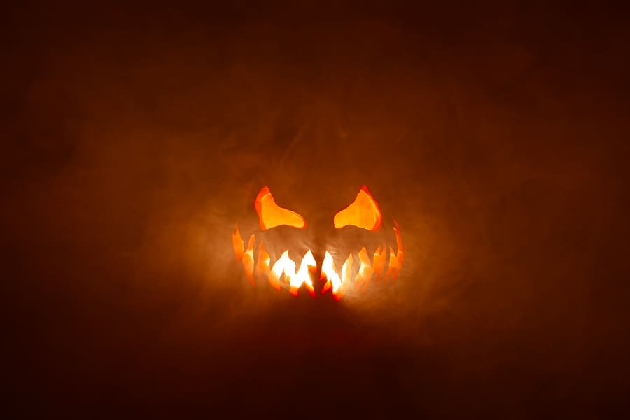 Scary Halloween jack o lantern face glowing in smoke and fire.