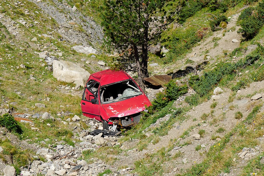 a crashed red car in the ravine
